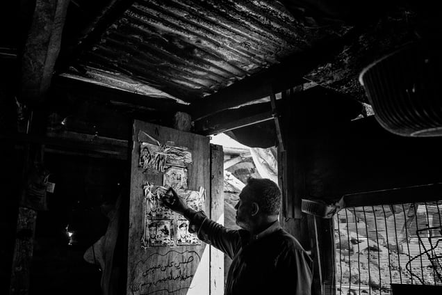 A man points at his son martyr’ poster in a makeshift house where he lives in Al Shejaiya neighborhood of Gaza city.