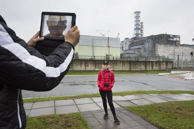 On a one-day visit to the Exclusion Zone, tourists have a few minutes for snapshots in front of the sarcophagus encasing Reactor 4. “This is as close as you can get, hurry up,” says the tour guide who asks visitors to stay on the paved paths “as radiation is substantially higher on the grass." Pripyat, Ukraine, 2013 © Gerd Ludwig / National Geographic Creative / National Geographic Magazine