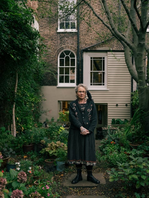 Carey in her garden, with her crow doll on her shoulder