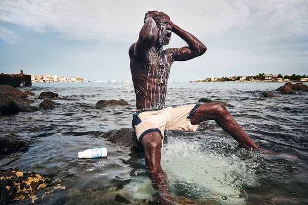 Kherou, a young wrestling champion, performs a ritual in the water of the sea while pouring milk over his body in order to obtain the reinforcement of a ghost who lives in the stones at the shore. Dakar, Sierra Leone, 11 August 2015.