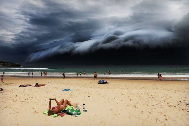 A massive 'cloud tsunami' looms over Sydney as a sunbather reads, oblivious to the approaching cloud on Bondi Beach, Sydney, Australia on 06 November 2015.