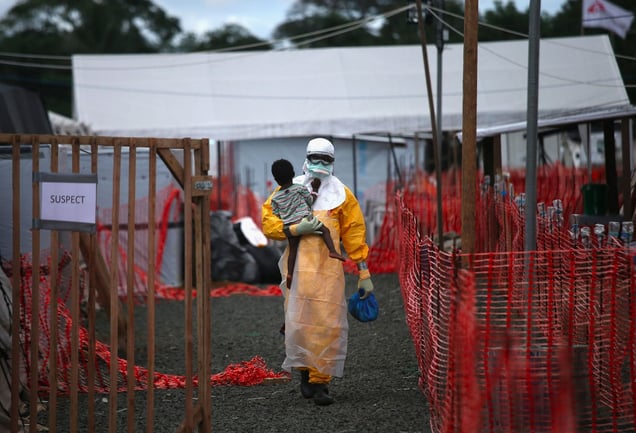 Suspect. An MSF health worker in protective clothing carries a sick girl at an Ebola treatment center. From the series "Ebola Crisis Overwhelms Liberian Capital." Winner of L’Iris d’Or, 2015 Sony World Photography Awards.
