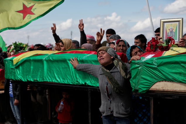 At a cemetery in Kobane, Syria, on 2 April, 2015, mourners stand by the coffine of thier loved ones who was  killed during clashes with the Islamic State in one of the frontlines of Kobane, Syria.