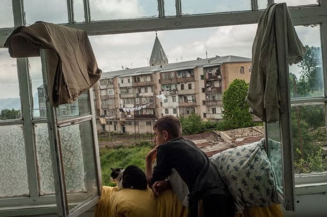 Stepanakert, Nagorno Karabach. A young man, with a cat, looks out of the window of his mother's apartment in Shusha during his last summer holiday before joining the Military School in Yerevan. The Nagorno-Karabakh Republic (NKR) is a de facto independent republic which is not recognized internationally.© Petrut Calinescu