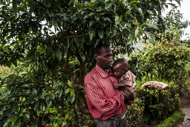 A longterm refugee from Rwanda shelters his son from rains in the village of Kivuye, in the eastern Democratic Republic of Congo.