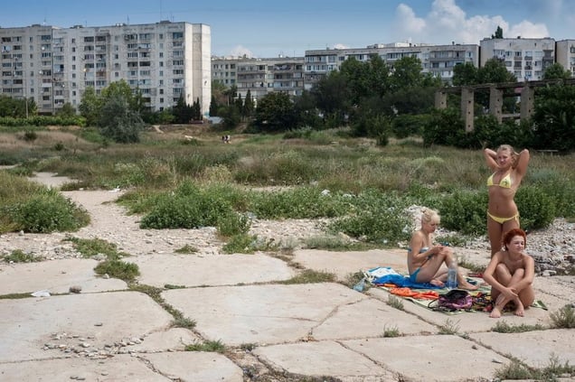 Crimea, Sevastopol. Three young women sunbathe at the edge of a run down Soviet era housing estate by the Black Sea (out of the picture).© Petrut Calinescu