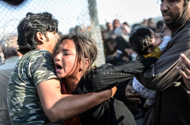 A refugee man holds a crying girl as others rush through broken down border fences to enter Turkish territory; Sanliurfa, Turkey, 14 June 2015.