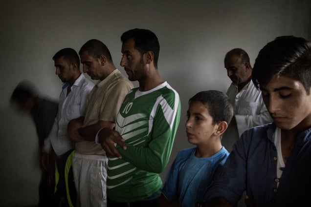Dibaga-Makhmur, Iraq. A group of displaced men from Jarallah pray before Iftar during the holy month of Ramadan. Their place of worship is inside a room (at a chicken farm) which was turned into a mosque. 04/07/2015.