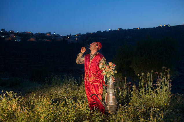 A coffee seller in traditional dress takes a break for a smoke, in Abwein on the West Bank.