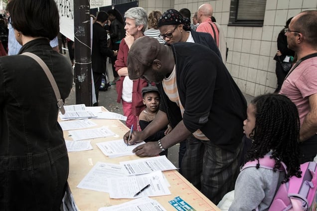 A man, with his family, is signing a petition against the closure of a "low-cost" public dental clinic nearby the estate. © Hugo Aymar