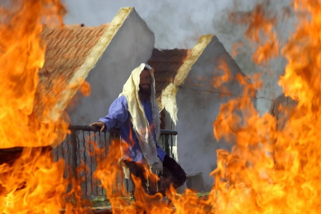 Homesh, Aug 05 - Behind a burning roadblock, a Jewish settler waits next to his home for Israeli soldiers to evacuate him © Natan Dvir