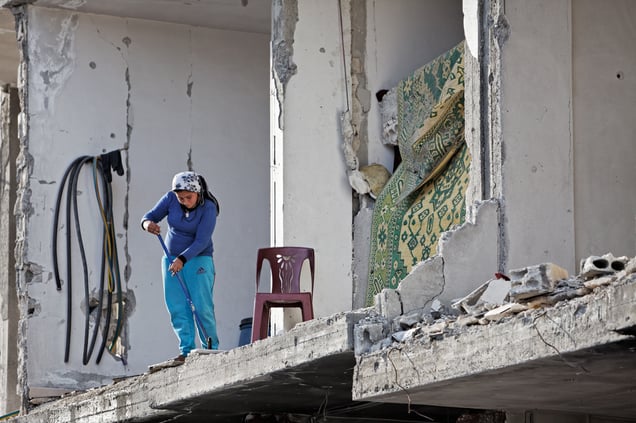 A Kurdish woman sweeps debris away from what is left of her house in Kobane on 2 April, 2015.