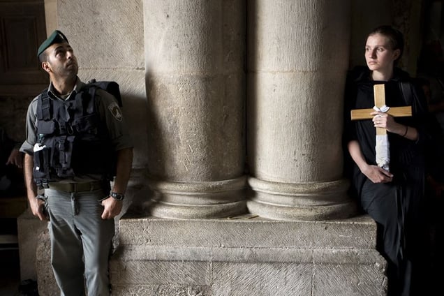 Jerusalem, Apr 08 - Israeli soldier stands next to Christian pilgrim holding cross at the entrance to the Holy Sepulcher church © Natan Dvir