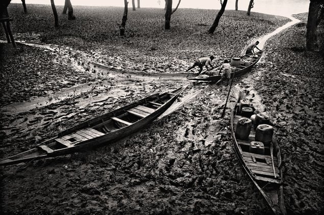 Shajhan Siraj and his brothers push boats through low tide into the sea. The boats are filled with fresh water which they have collected inland. It takes the brothers up to three hours to make the journey each day. Datinkhali, Satkhira. © Munem Wasif/VU'