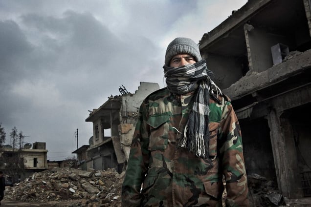 A Syrian man poses for a portrait on February 8, 2013 in the rubble of buildings in Azaz, Syria which were destroyed by a government airstrike last year.  © Nish Nalbandian