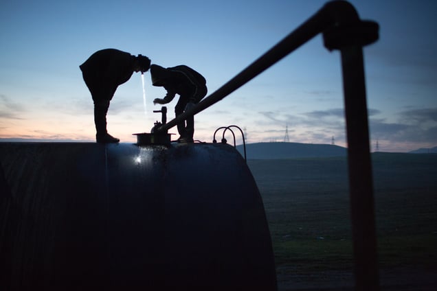 Jamal, 17, and Azdar, 16, watch as fuel oil is pumped into a storage drum at dawn.