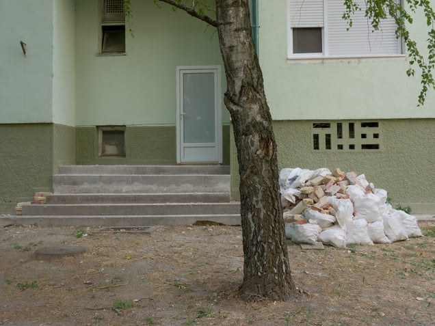 The rear side of a residential block. Later plastic fittings and renovation debris mark the ongoing adaptation of an older housing structure.