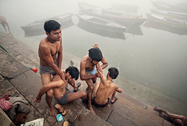 Varanasi, India: Young Brahmans, members of the highest Indian caste, on the shores of the sacred river of Ganges at sunrise massaging each other. Later on they will ritually bathe and clean themselves. © Matjaz Krivic
