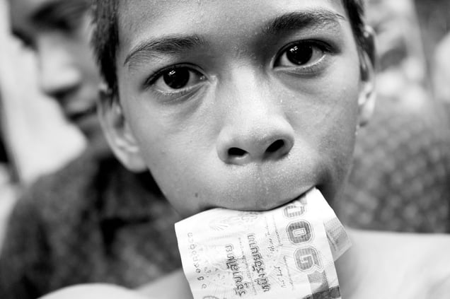 A boy with money in the mouth. After the boxing match, the winner goes around and collects money from tourists. But he is not allowed to keep the money, most of it takes the coach. © Sandra Hoyn