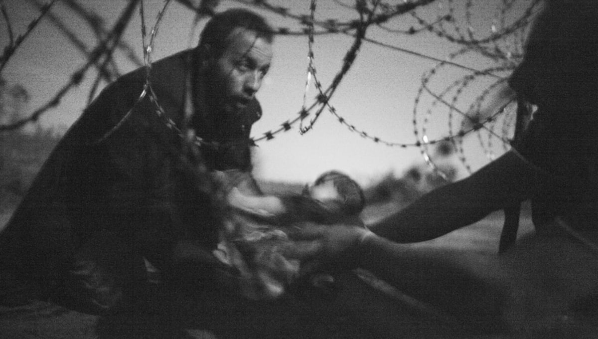 A man passes a baby through the fence at the Serbia/Hungary border in Röszke, Hungary, 28 August 2015.