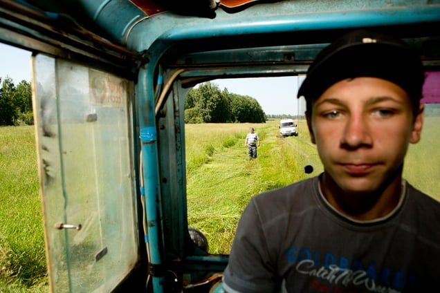 Vova in the tractor cabin and his foster father in the background near the village of Molot.