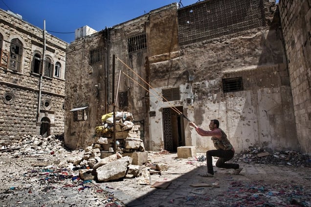 An FSA fighter prepares to fire a rock with a slingshot toward Syrian army positions in the Old City of Aleppo on April 25, 2013. The historic Old City, a UNESCO World Heritage Site, has sustained a significant amount of damage during fighting between opposition groups and the Syrian government during the ongoing conflict. © Nish Nalbandian