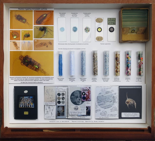 Installation drawer. The original antique specimen drawer highlights the connection with plastic, showing images of plankton ingesting plastic particles, and research/sketch books spreads. Microscope slides and test tubes show samples of micro plastic particles recovered from oceans around the world, alongside micro beads collected from toothpaste and facial scrubs.