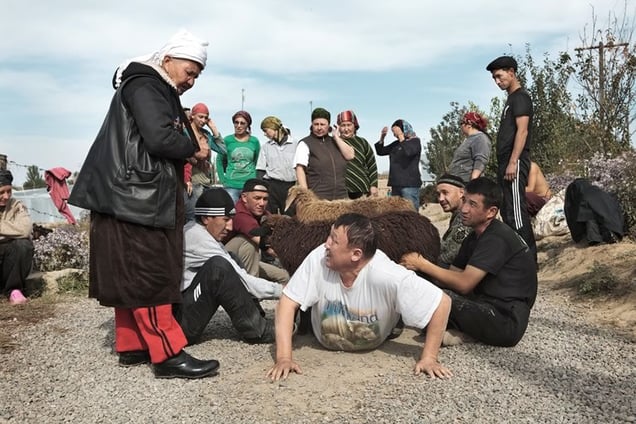 A ritual. People have to crawl under the goat back and forth, before the goat is killed and the blood is spilled onto the people. The purpose of the ritual is to pass all the bad energy and karma onto the sheep.
From the series Apashka by © Pavel Prokopchik