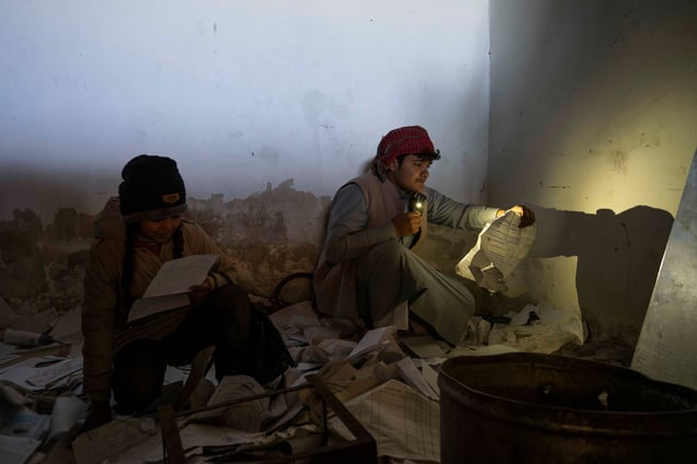 Prison / Seidnaya / Syrie
 Assis dans une salle sombre ses enfants cherches un indice en scrutant chaque registres trainant au sol