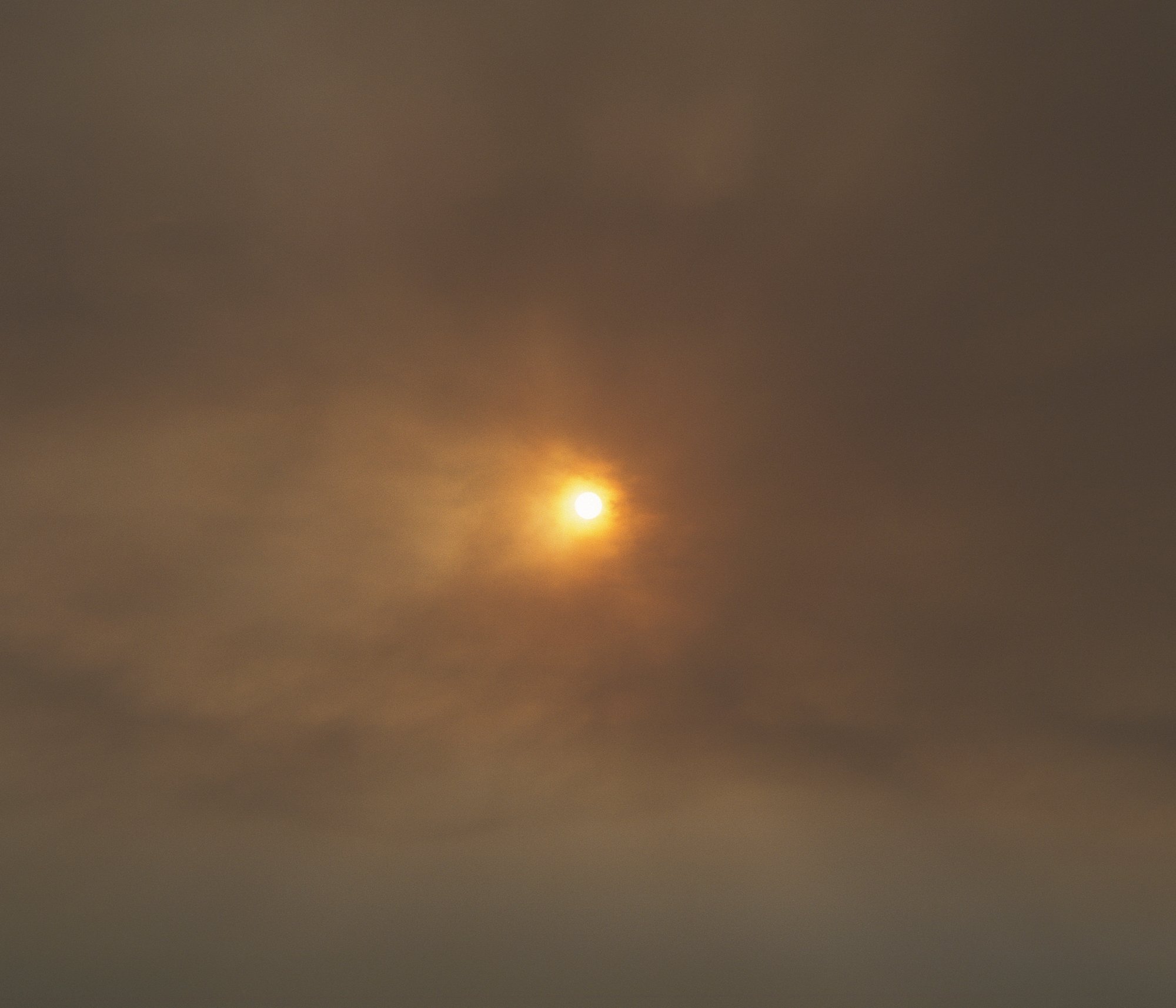 The sun. Sun obscured by a cloud of smoke from a forest fire. The region of Galicia experiences a devastating number of wildfires, contributing to 80% of forest fires in Spain. 2021 set a record with over 9,000 registered fires, consuming more than 35,000 hectares of land. These disasters not only wreak havoc on biodiversity but also have adverse consequences on air quality and the health of local communities. © Carlos Folgoso Sueiro