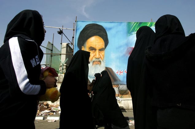 Iranian women walk past a portrait of Ayatollah Ruhollah Khomeini - the leader of the 1979 revolution and founder of the Islamic Republic of Iran. Tehran, IRAN - December 2008 © Copyright 1979-2009 Alfred Yaghobzadeh. All rights reserved.