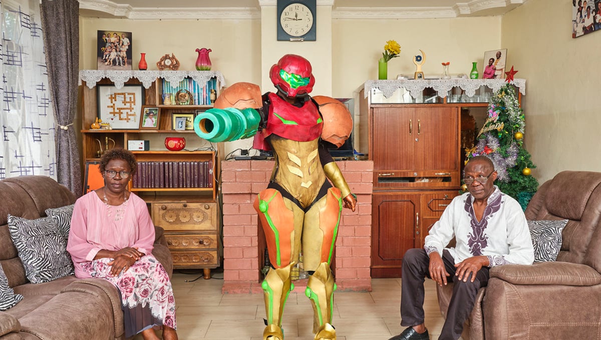 Jess (27),  poses with her parents in their living room in Nairobi (Kenya); she works as a designer and has been practicing cosplay since 2013. In photo she plays “Samus Aran" the main protagonist of the video game series “Metroid".