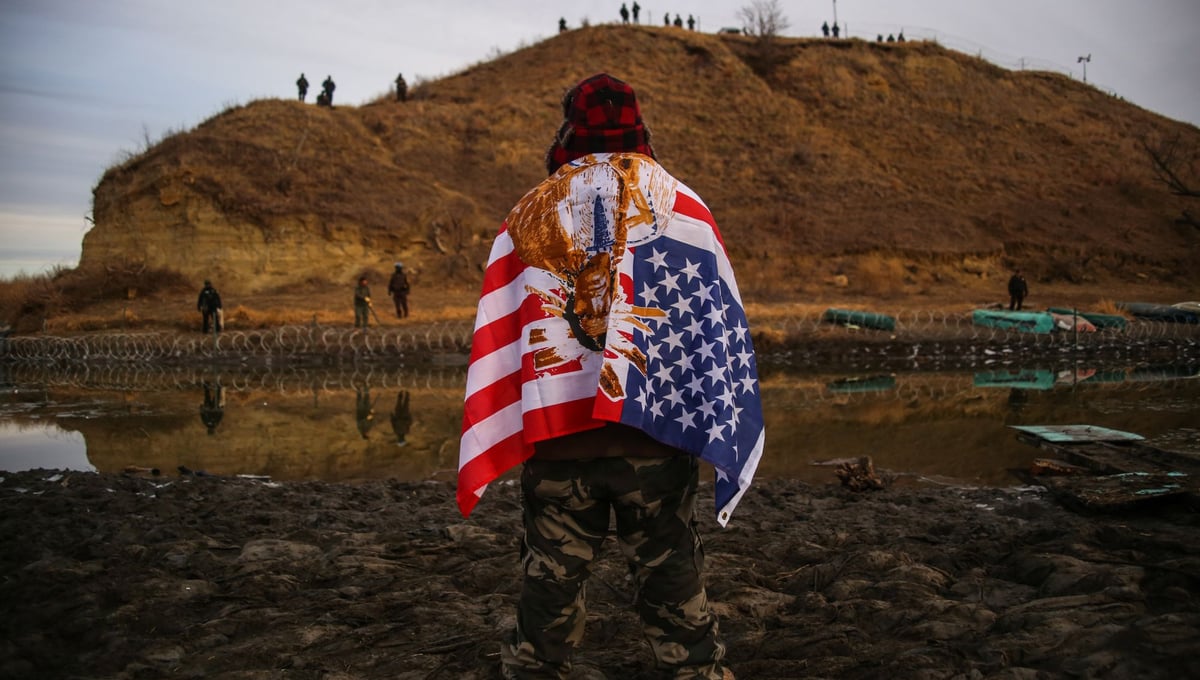 Andrew Waupekenay of the Menominee Indian Tribe of Wisconsin stands as he faces authorities on the other side of the Cantapeta Creek which runs into the Missouri River after barbed wire was placed along the shore near the Oceti Sakowin Camp on Army Corps of Engineers land bordering the Standing Rock Indian Reservation in Cannon Ball, North Dakota in November 2016.