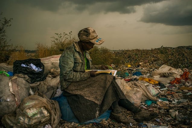1st Prize Contemporary Issues Single © Micah Albert, USA, Redux Images. 03 April 2012, Nairobi, Kenya. Pausing in the rain, a woman working as a trash picker at the 30-acre dump, which literally spills into households of one million people living in nearby slums, wishes she had more time to look at the books she comes across. She even likes the industrial parts catalogs.