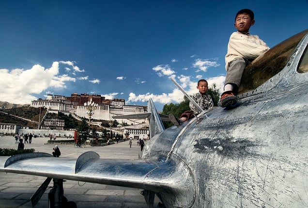 Lhasa, Tibet: Tibetan children are playing on a military airplane, a symbol of occupation that the Chinese authorities erected on the square opposite the Potala palace, a symbol of Tibetan Buddhism.  © Matjaz Krivic