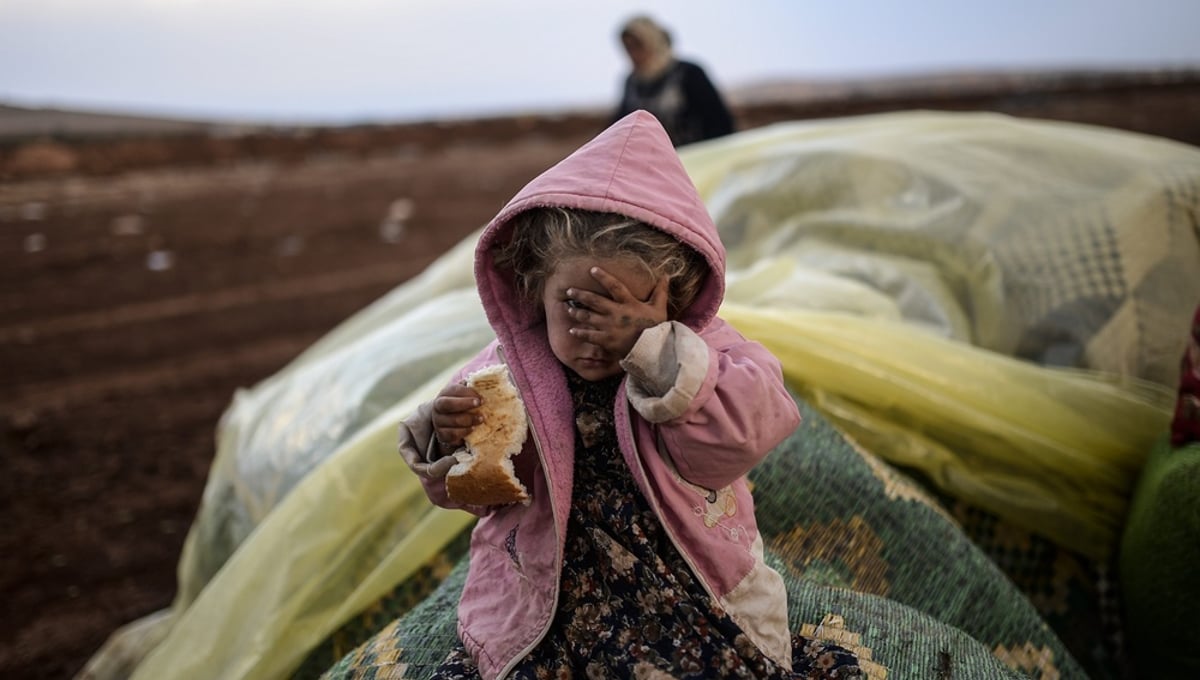 Near the southeastern town of Suruc, Sanliurfa province, Turkey, October 2, 2014. A Kurdish woman and her daughter wait after crossing from Syria into Turkey, with mortar fire on both sides. © Bülent Kiliç / AFP