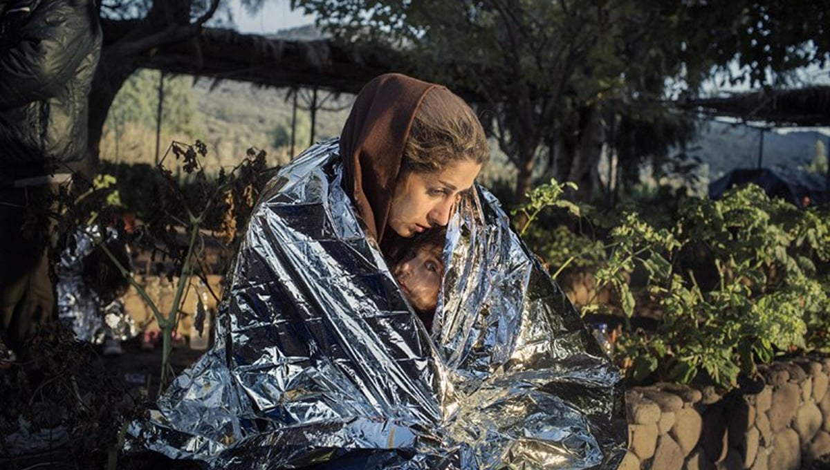 A mother and child wrapped in an emergency blanket after disembarking on the beach of Kayia, on the north of the Greek island of Lesvos, Oct. 18, 2015 - Crossings Exhibition