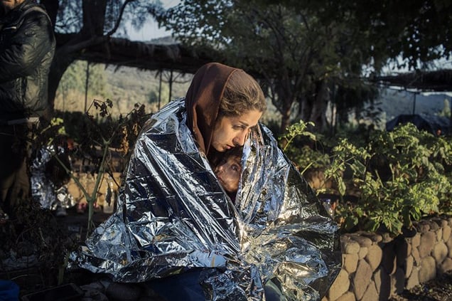 A mother and child wrapped in an emergency blanket after disembarking on the beach of Kayia, on the north of the Greek island of Lesvos, Oct. 18, 2015 - Crossings Exhibition