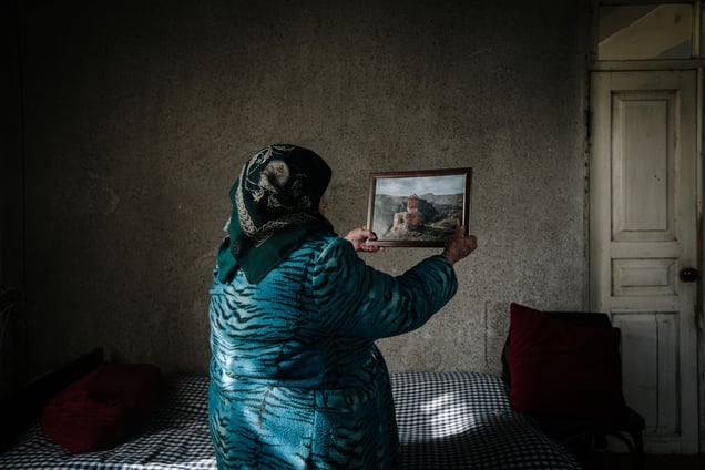 Yepraksia holds an image of the location from whence she recalls escaping with her family. This is the first time she has seen it in 100 years.