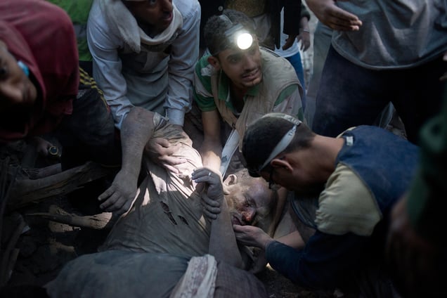 Rescuers and family members attempt to pull a man from the rubble of his home on Friday, June 12, 2015 in Sana'a, Yemen. Four houses collapsed after a Saudi airstrike in the city. It is unclear if an unexploded rocked landed inside the homes, or the pressure of a nearby explosion caused them to collapse. © Alex Potter
