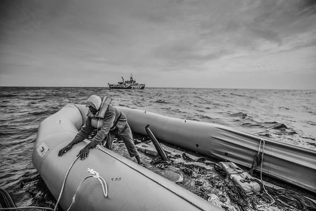 A migrant waits to be rescued from a deflating rubber boat
