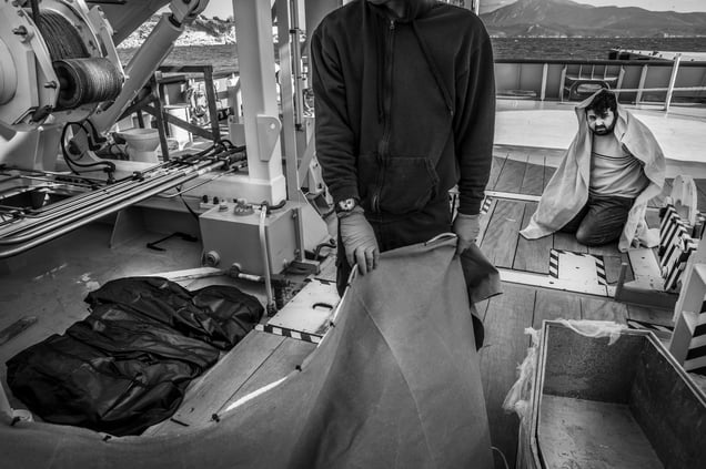 A Turkish smuggler is made to look at the bodies of three Syrian refugee children who drowned after he caused the boat they were on  to capsize off the Greek coast