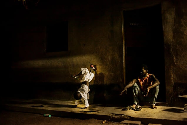 A young boy does a handstand while is father sits exhausted in outside their home in the village of Attienkru outside Bouake, Ivory Coast on Tuesday November 11, 2014.  (Pete Muller/Prime for National Geographic)