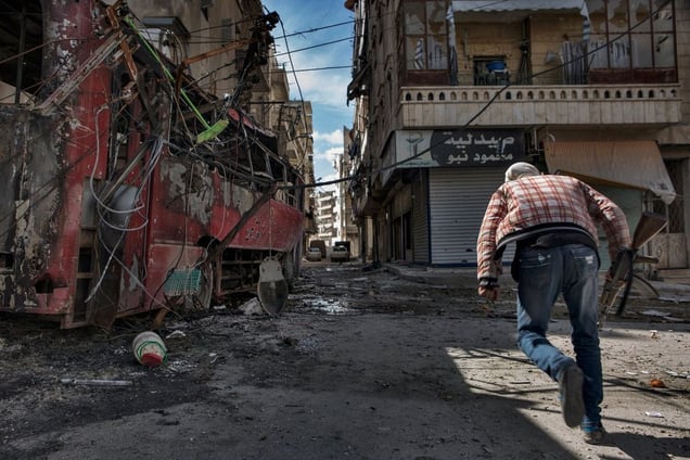 A YPG fighter sprints across an intersection to avoid Syrian government army sniper fire in the Ashrafieh district in Aleppo on April 20, 2013. © Nish Nalbandian