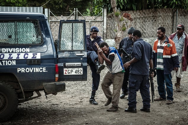 A policeman beats a man on the street in the town of Minj, Jiwaka Province. The man was suspected in a sexual assault attempt and police arrested him, using force to take him to the police station for interrogation.