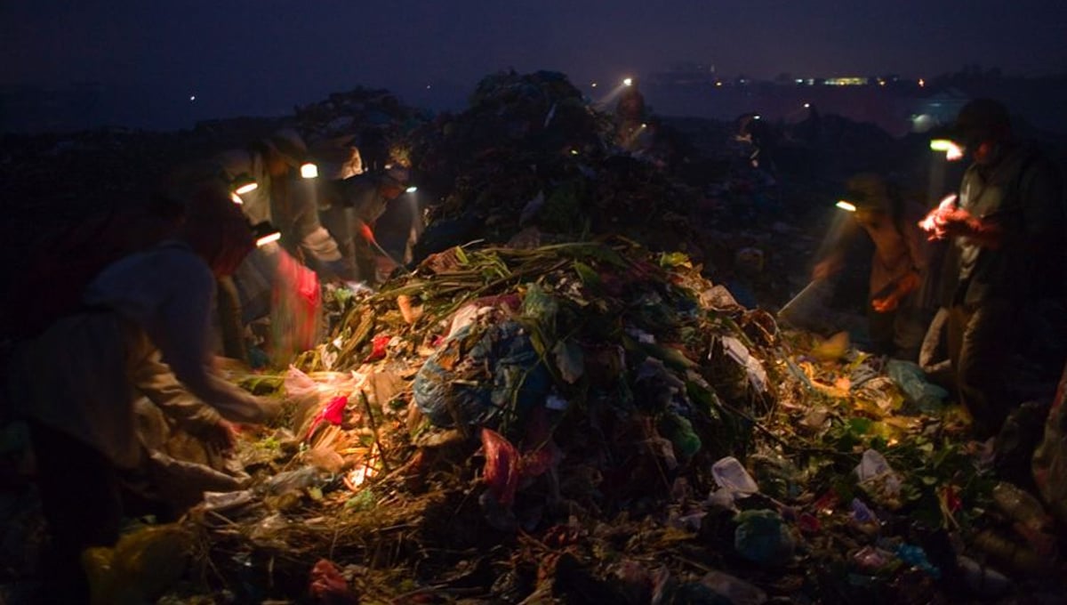 Recycling workers, picking through the waste for plastic bags, in the middle of the night, on Smokey Mountain Rubbish Dump. They rent miner's lamps and batteries for 25 cents, which is about a quarter of what they will make on a night shift.
© Nigel Dickinson.