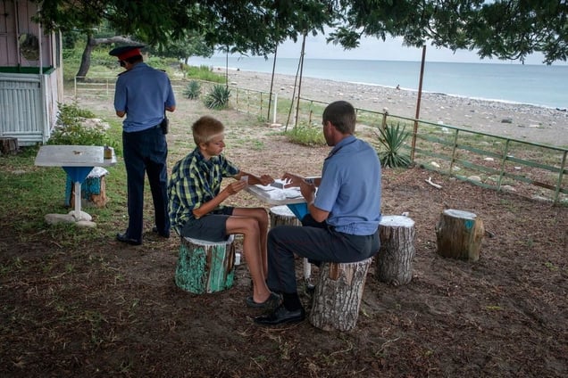 Georgia, Sukhumi, AbkhaziaPolicemen chat and play cards with a boy near the beach in Sukhumi.© Petrut Calinescu