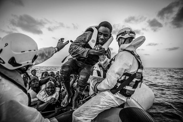 MOAS search and rescue team pull a migrant from an overloaded rubber boat