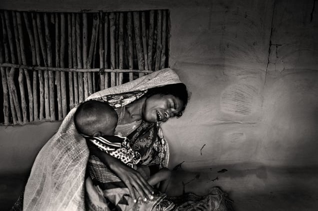 A mother grieves as her child lapses into unconsciousness. The tumour on her child's back has worsened. Her husband is fishing and will not return that day. Chuna, Satkhira. © Munem Wasif/VU'