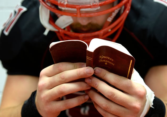 Photo by Bernard Brault, LA PRESSE | Mathieu Rioux-Paquette, of the Lynxsof the Collège Édouard-Montpetit, reads the New Testament before the game against the Élansof FX Garneau.